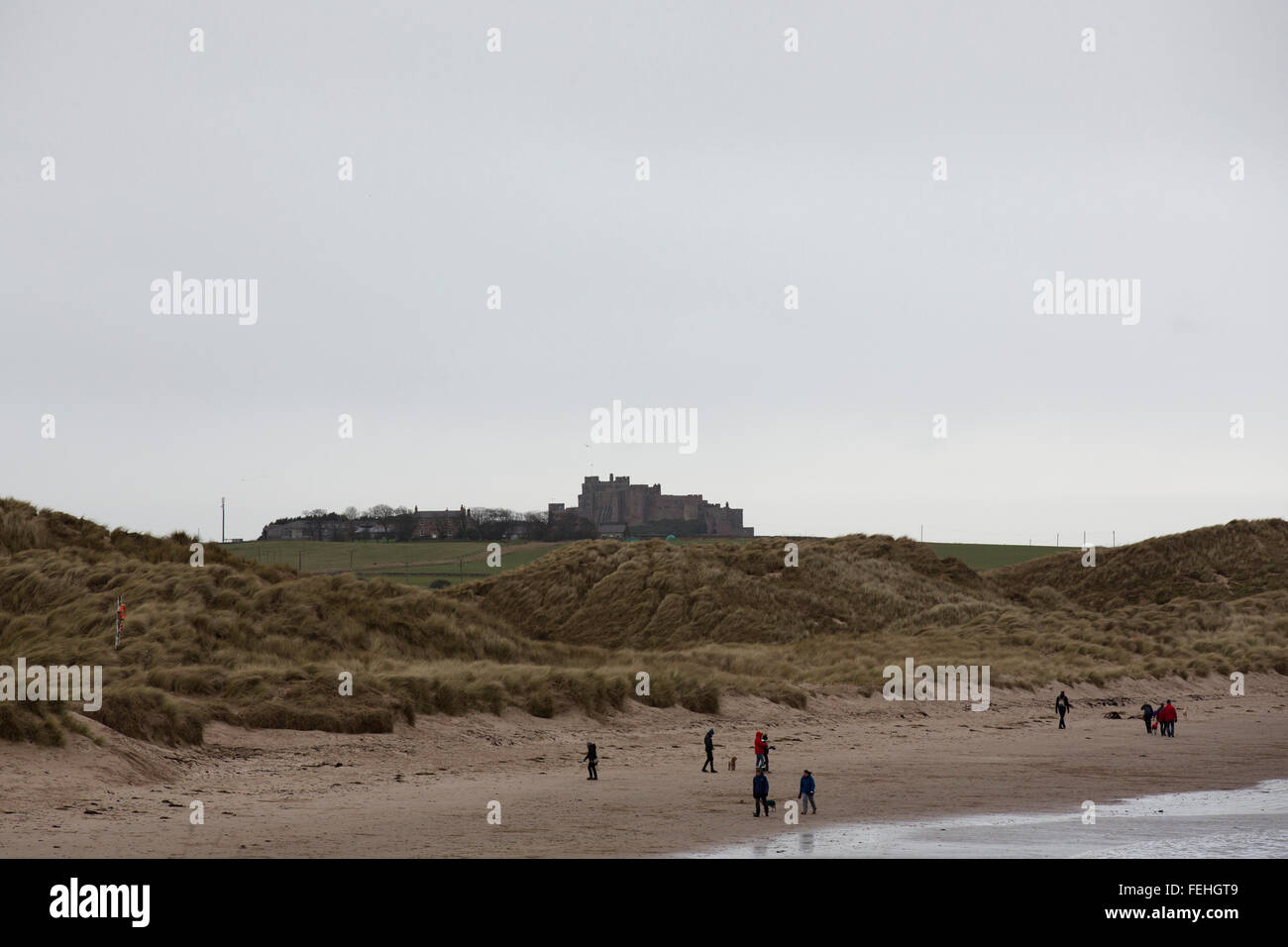 Northumberland, UK. 7th February, 2016. UK Weather: People on the beach near North Sunderland and Seahouses in Northumberland, England. Waves with whitecaps break next to the beach. Credit:  Stuart Forster/Alamy Live News Stock Photo