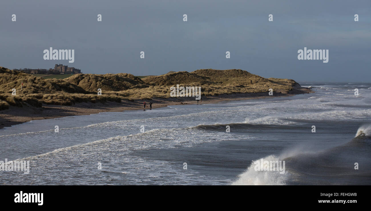 Northumberland, UK. 7th February, 2016. UK Weather: People on the beach near Bamburgh Castle in Northumberland, England. Waves with whitecaps break by the beach. Credit:  Stuart Forster/Alamy Live News Stock Photo
