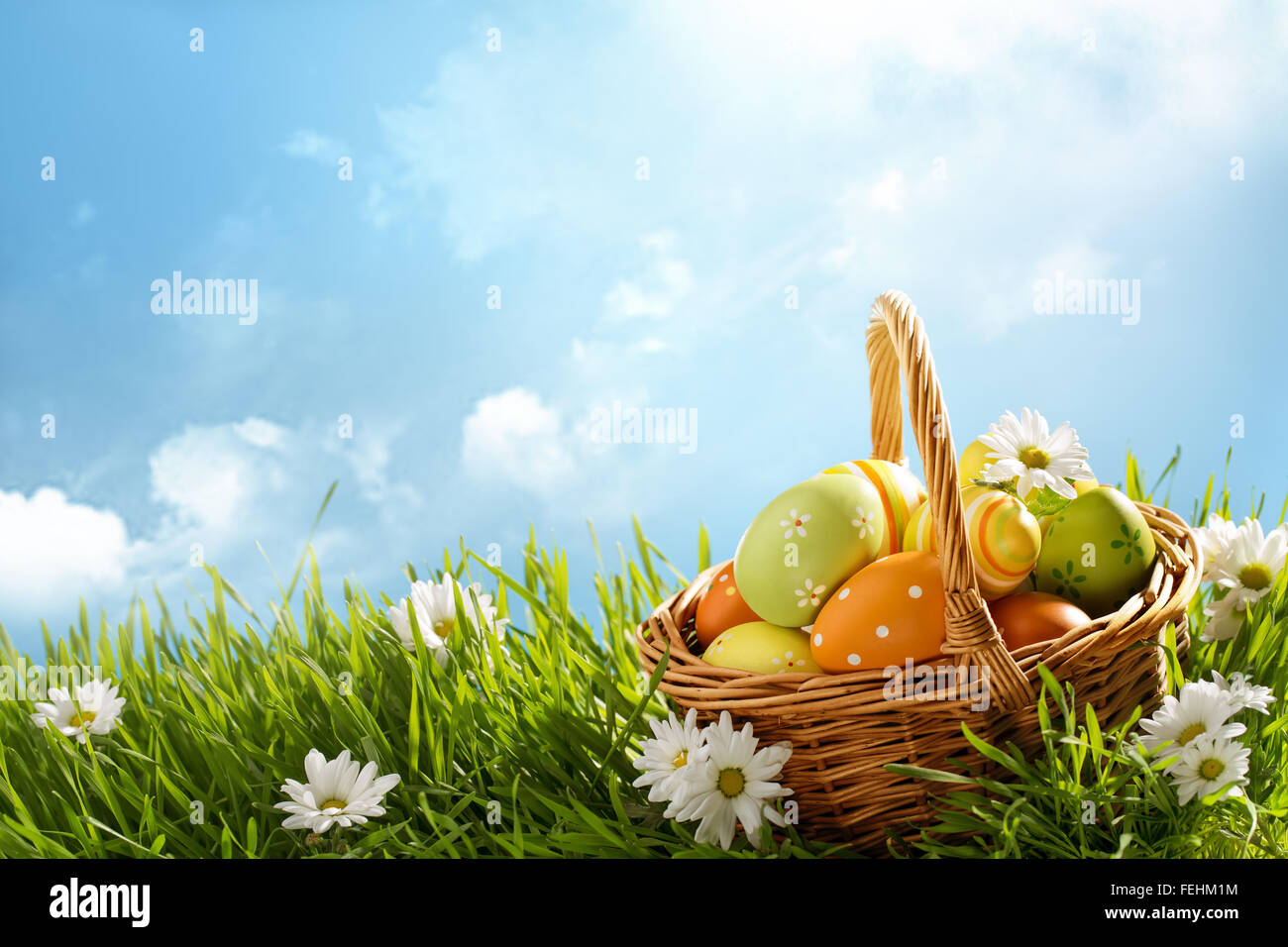 Basket of easter eggs on green grass at sunny day. Stock Photo