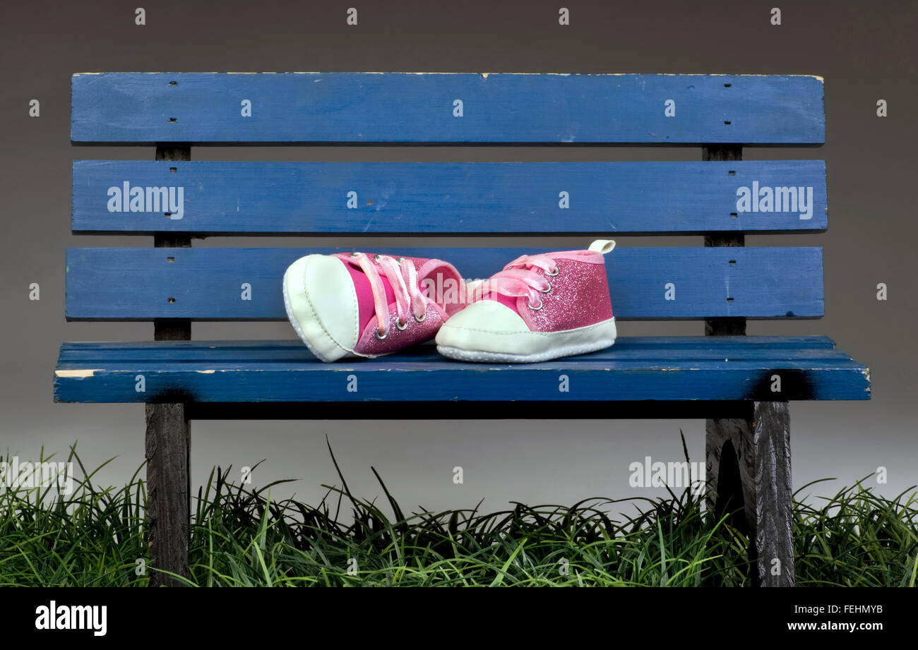 Little cute pink shoes on blue park bench. Stock Photo