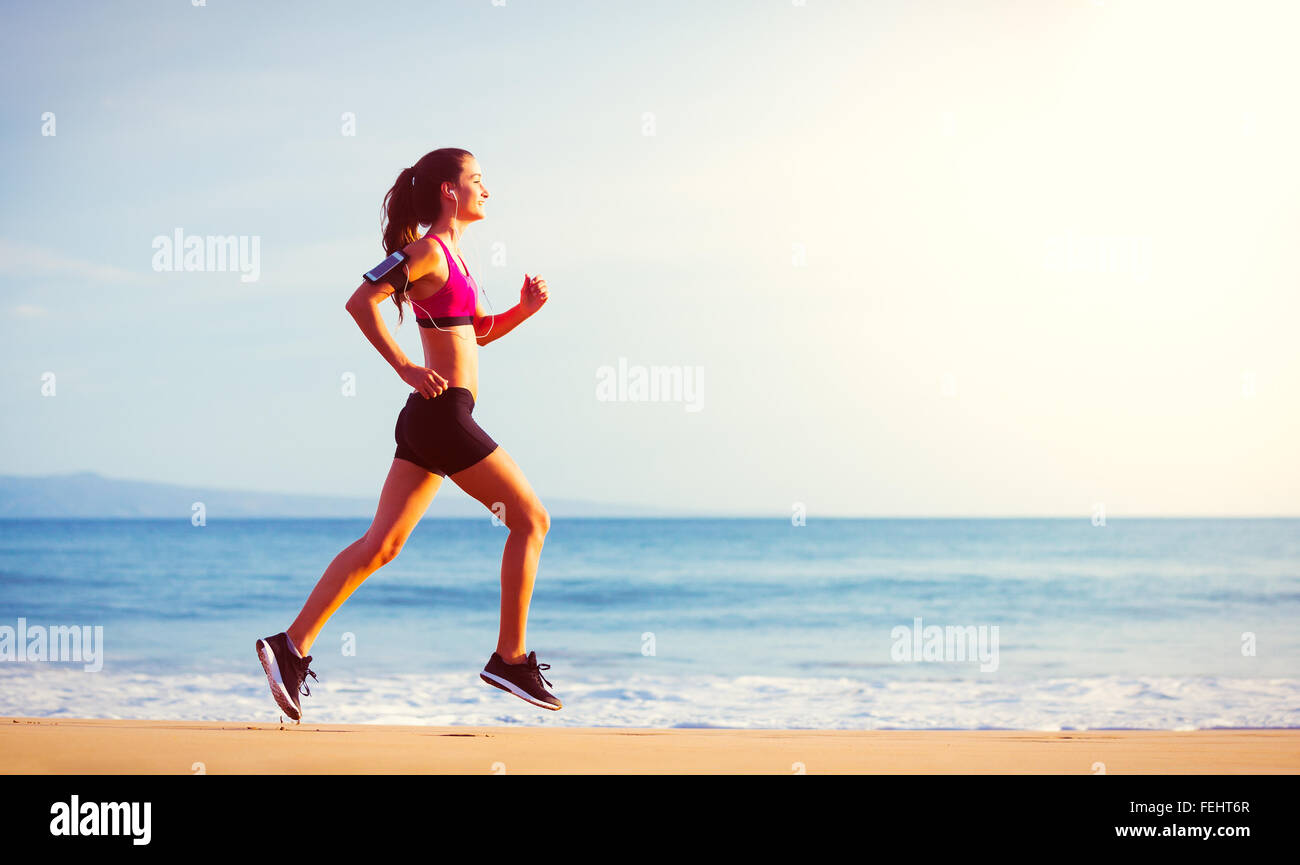Fitness Woman Running by the Ocean at Sunset Stock Photo