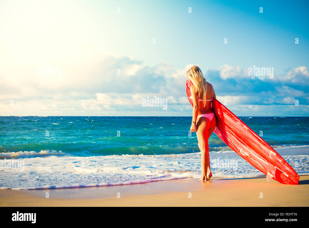 Beautiful Blonde Surfer Girl on the Beach at Sunset. Summer Lifestyle. Stock Photo
