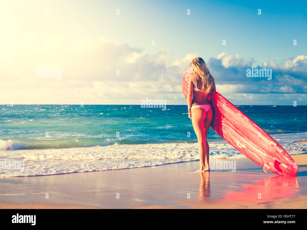 Beautiful Blonde Surfer Girl on the Beach at Sunset. Summer Lifestyle. Stock Photo