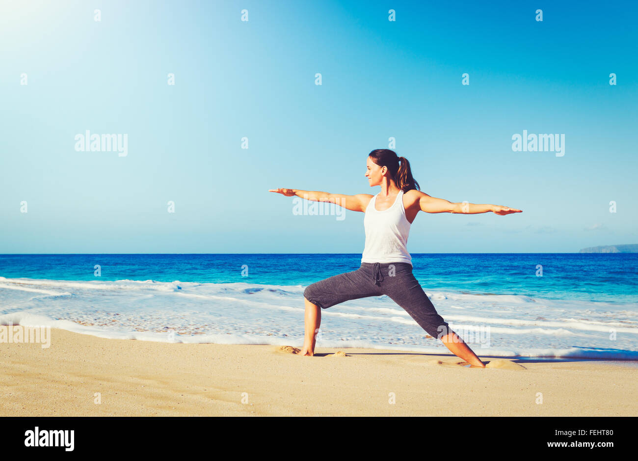 Healthy Lifestyle Concept, Beautiful young woman stretching practicing yoga on the beach Stock Photo