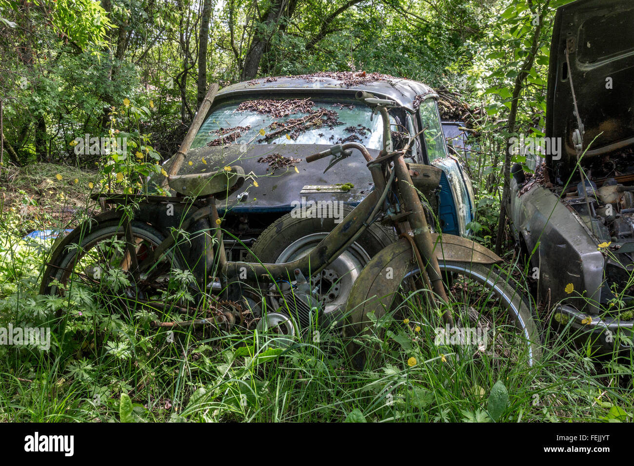 Old beaten up Citroen and a scooter in a car graveyard Stock Photo