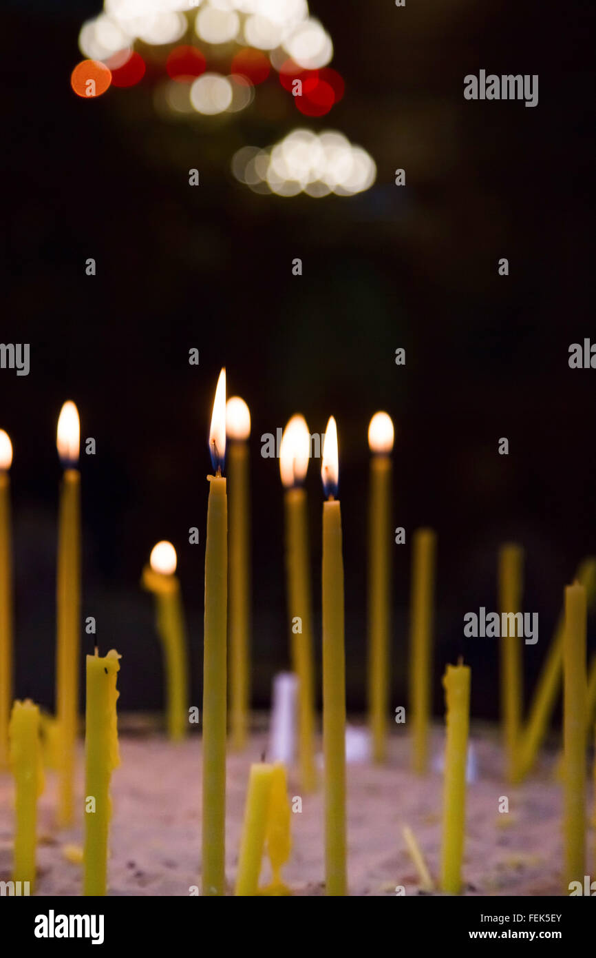 Lighted wax candles in a church burning in the twilight Stock Photo