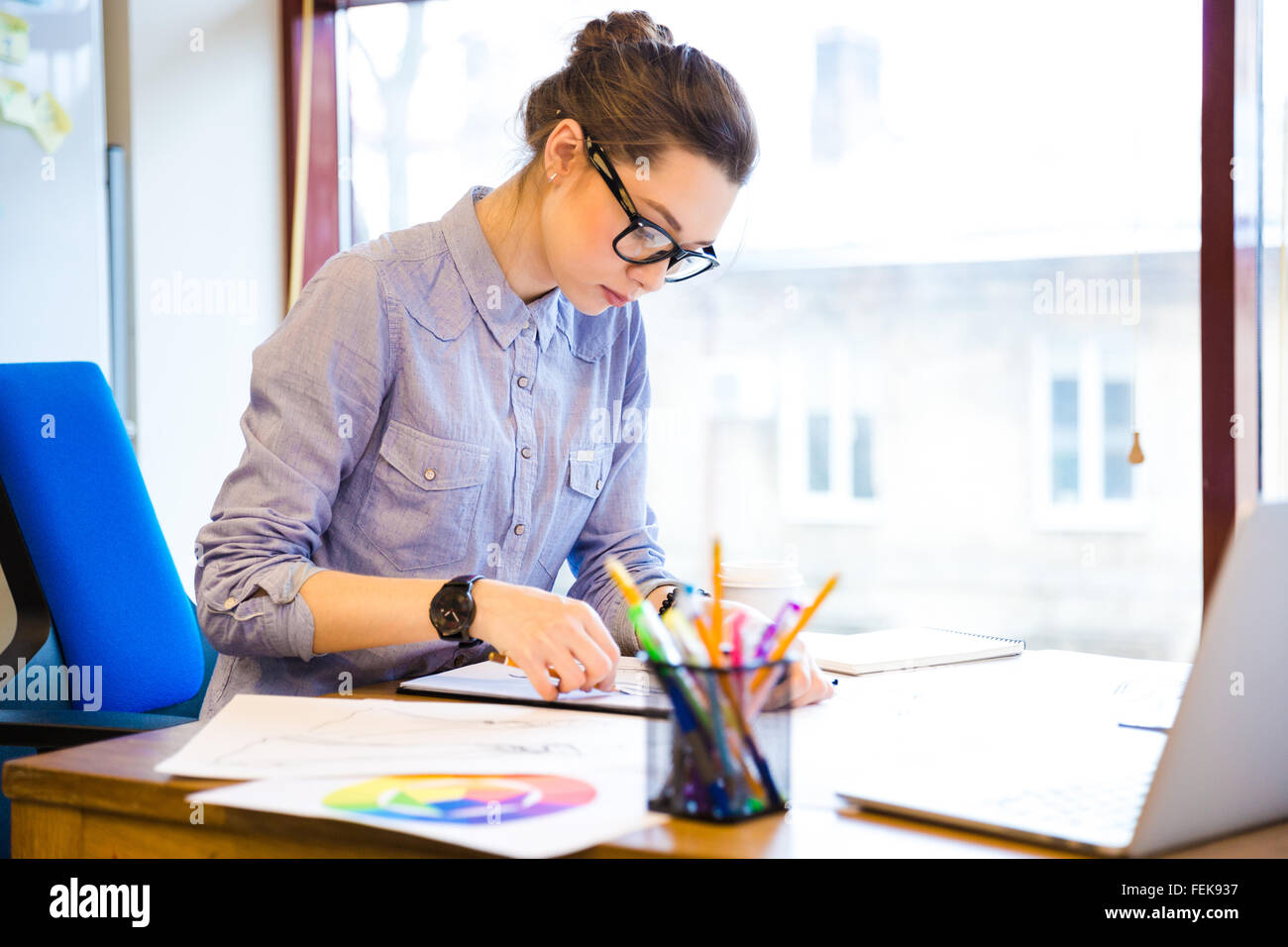 Concentrated pretty young woman fashion designer sitting and drawing ...