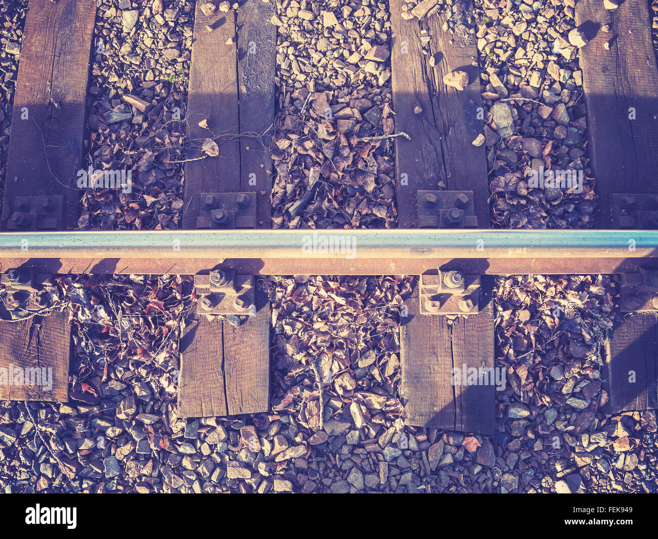 Retro filtered photo of railway track with wooden sleepers. Stock Photo