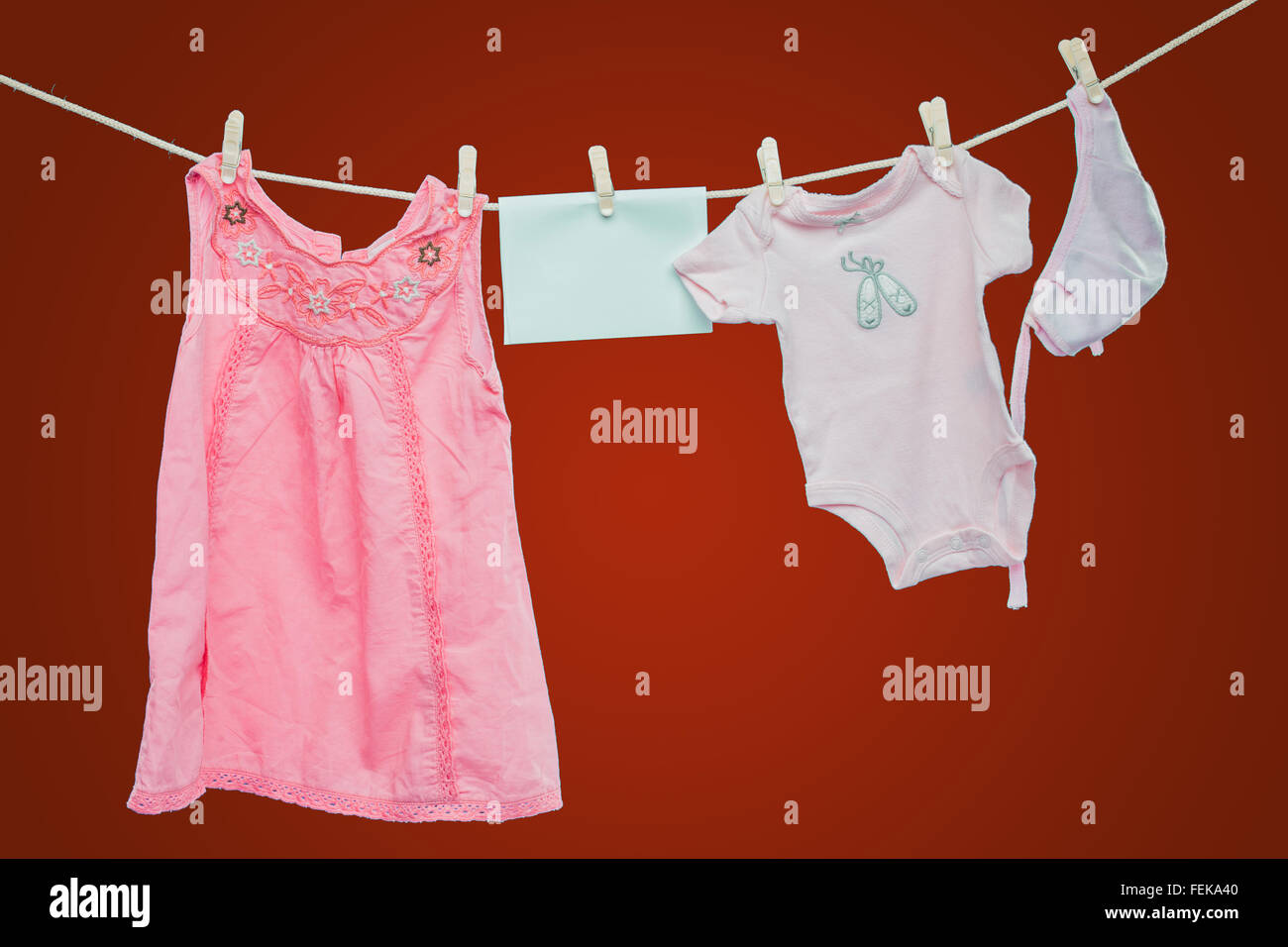 Baby goods hanging on the clothesline on red background Stock Photo