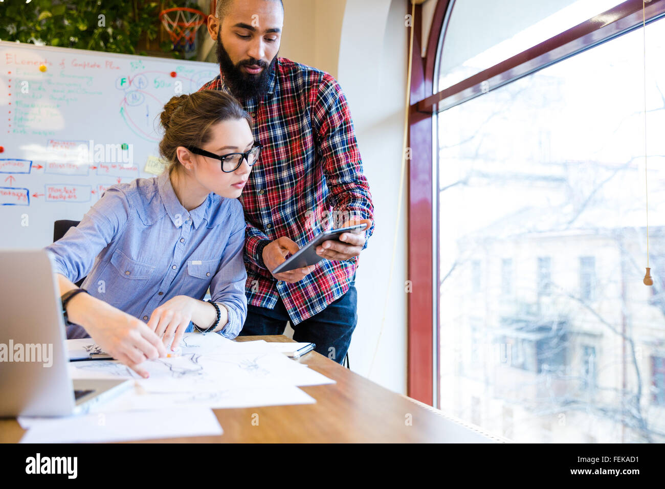 Two young woman and man fashion designers working and using tablet together Stock Photo