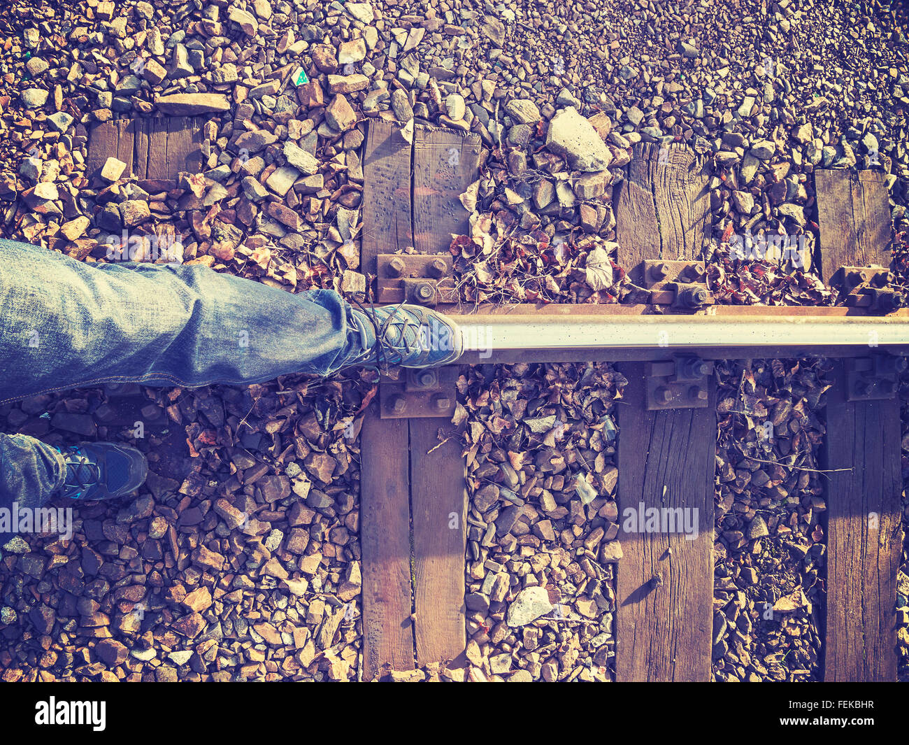 Vintage stylized legs walking on rail track, concept picture. Stock Photo