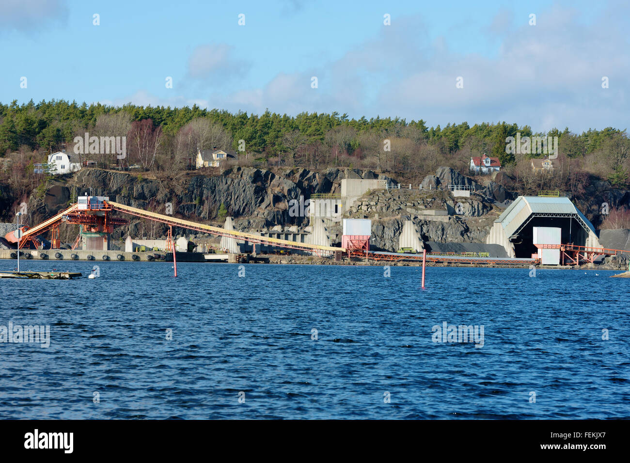 A loading facility in a quarry close to water. Gravel and stone is transported on curved conveyor belts up to the tower that dep Stock Photo