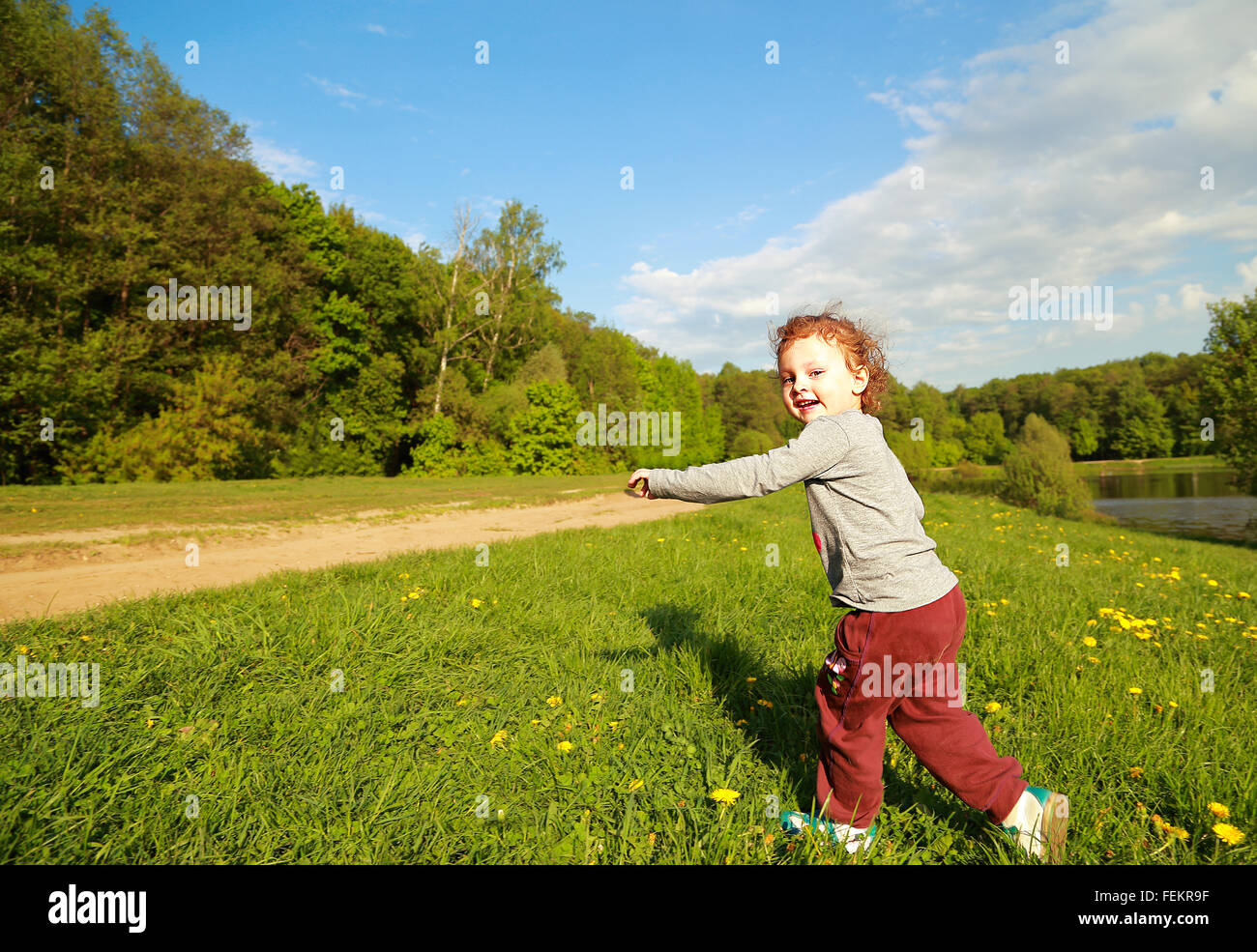 Running happy kid girl outdoors bright summer background Stock Photo