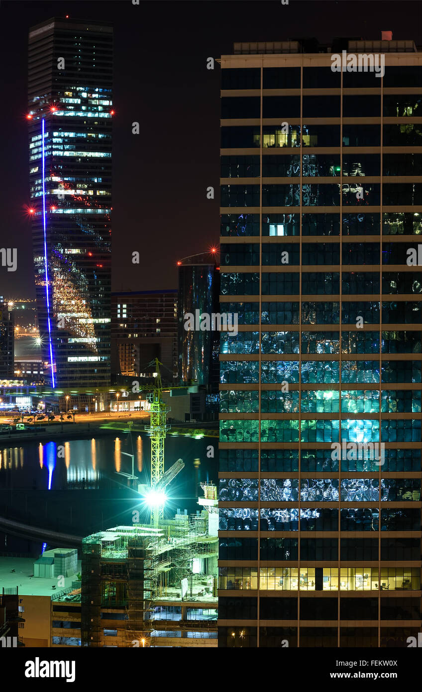 Office buildings in Dubai at night reflecting colorful lights Stock