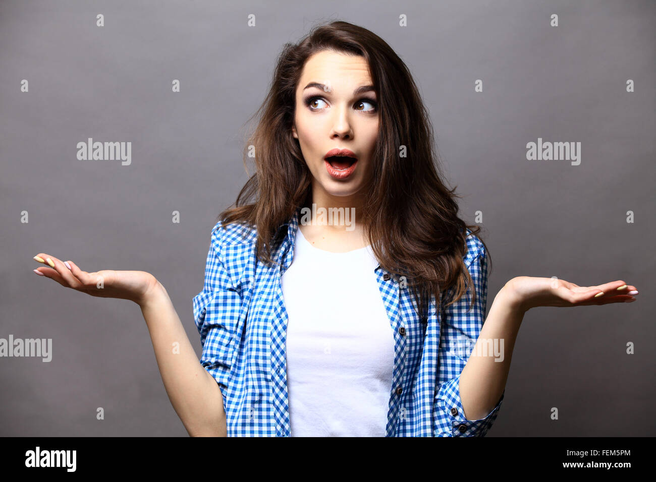 Surprised young woman over gray background Stock Photo - Alamy