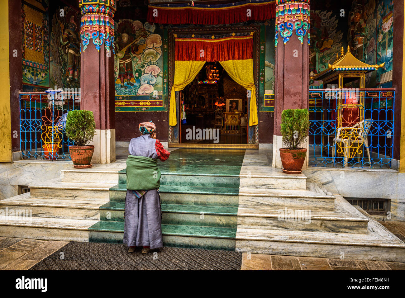 Old woman wearing traditional costume prays in front of a buddhist temple in Kathmandu, Nepal Stock Photo