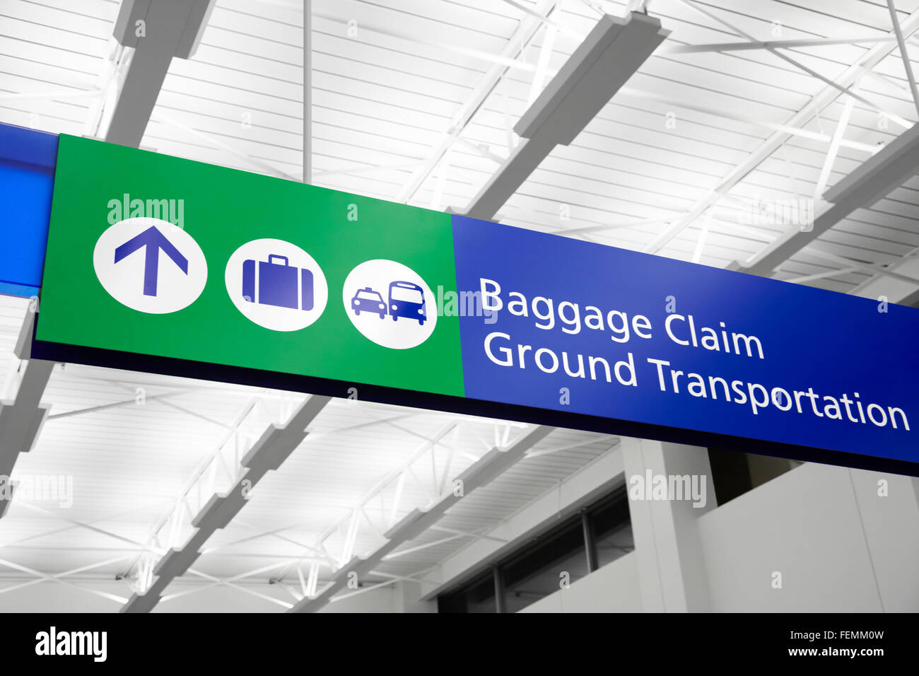 Airport baggage claim and ground transportation sign with suitcase, bus, and taxi symbols. Sign is blue and green. Stock Photo