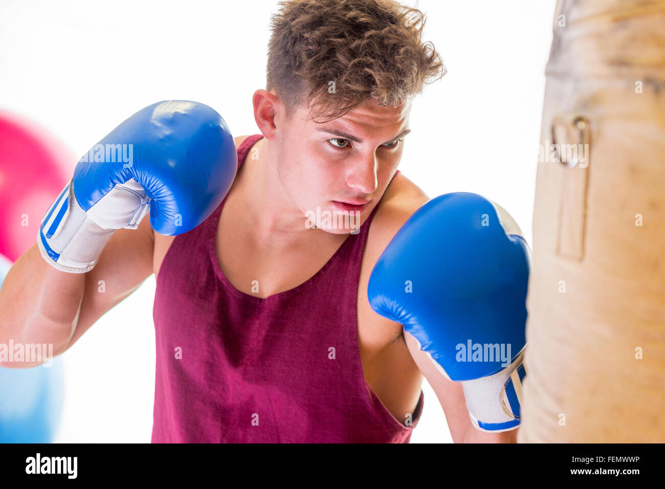 Attractive young man in boxing position hitting a punching bag Stock