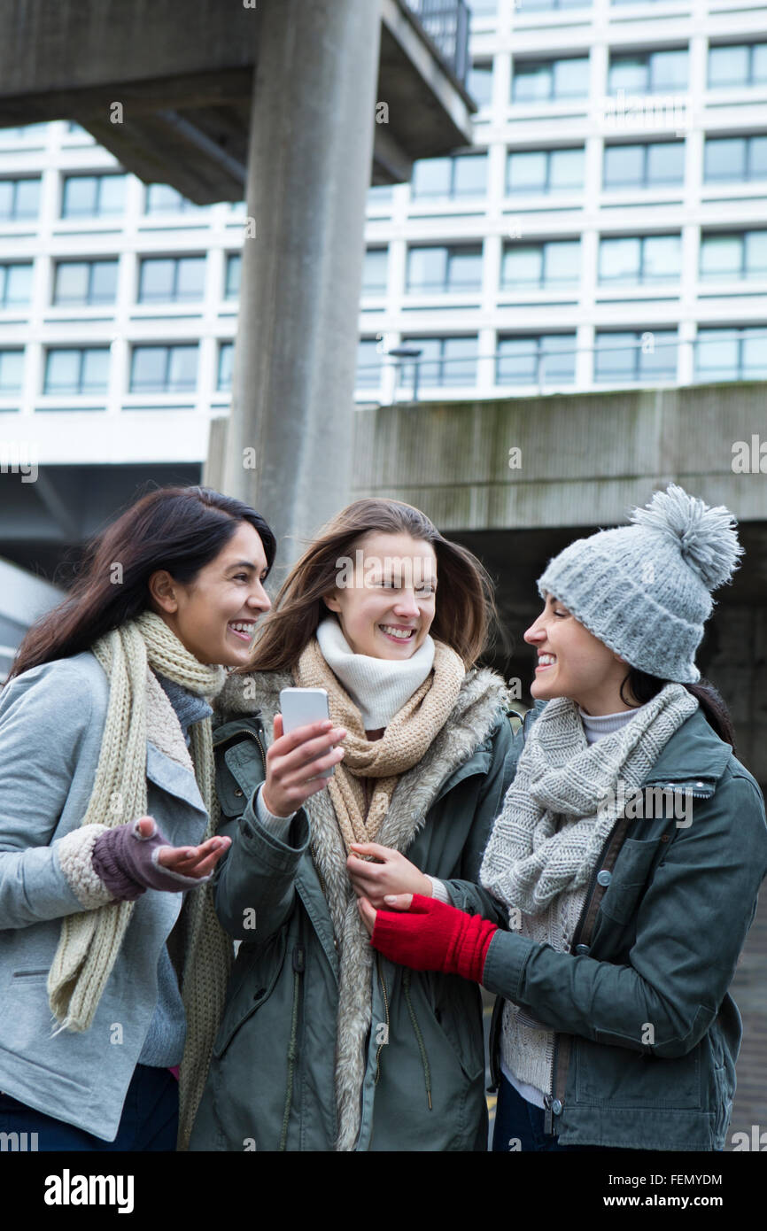 Three young women in the city, looking at something on a smartphone. Stock Photo