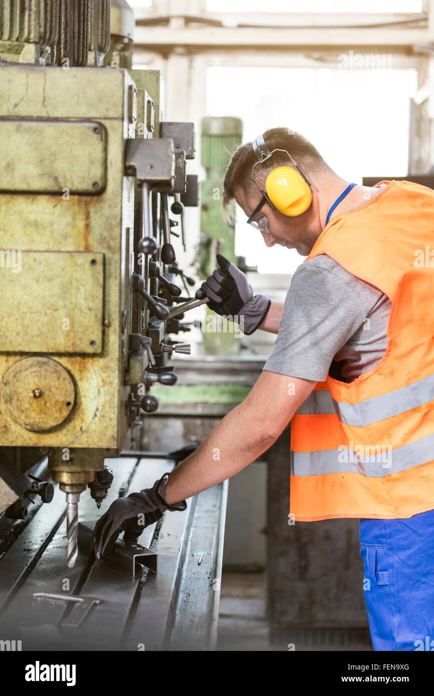 Worker in protective workwear operating machinery in factory Stock Photo