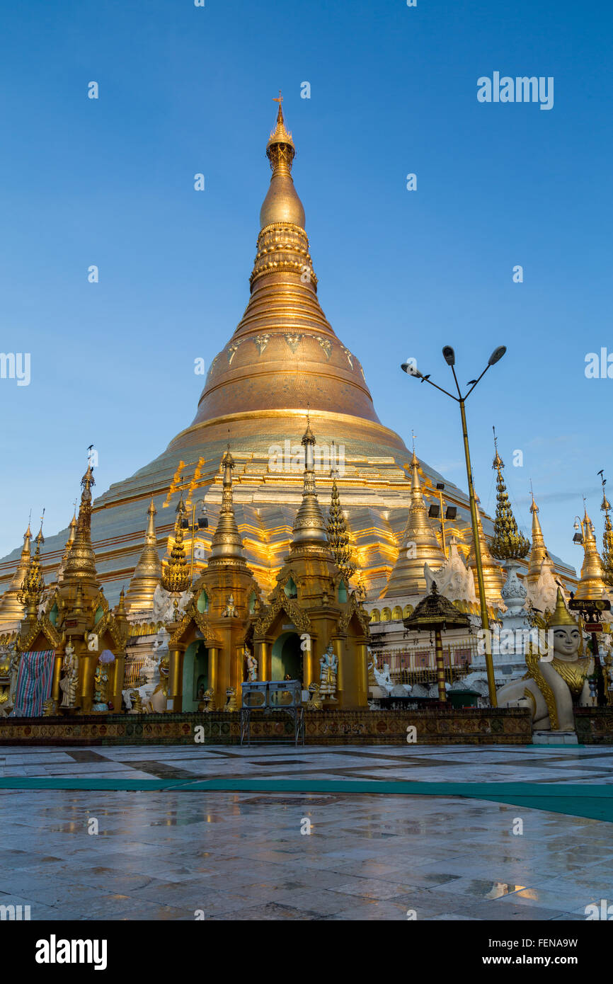 The iconic Shwedagon pagoda glows in a beautiful soft gold light at dawn - portrait Stock Photo