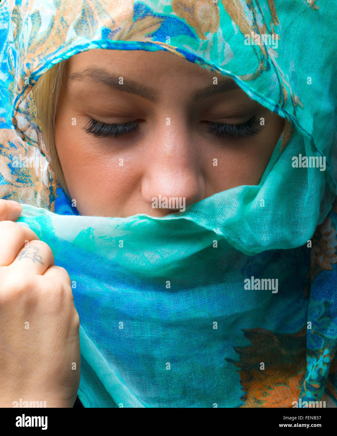Potrait of woman wearing a blue scarf with eyes closed Stock Photo