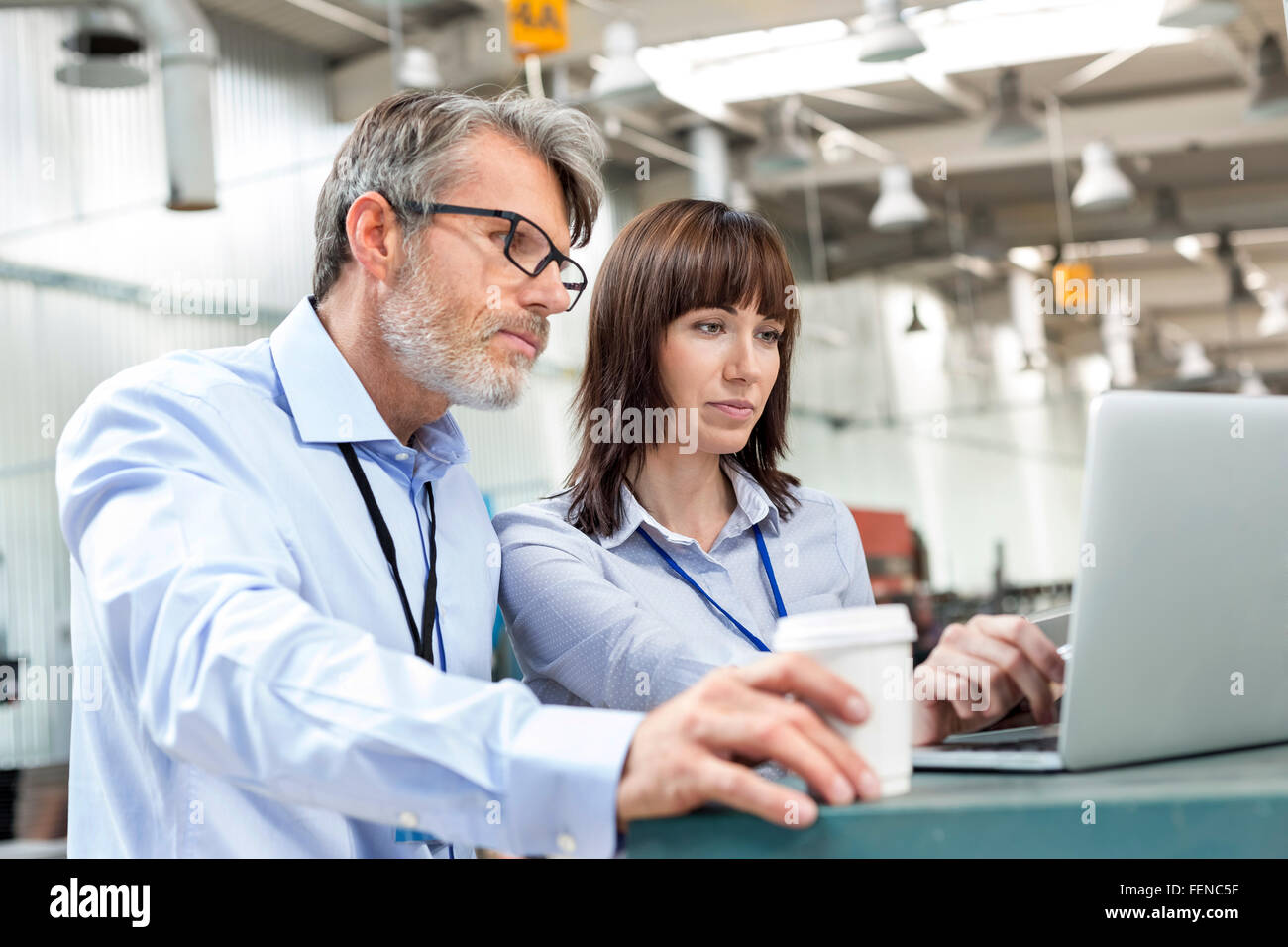 Business people with coffee at laptop in factory Stock Photo
