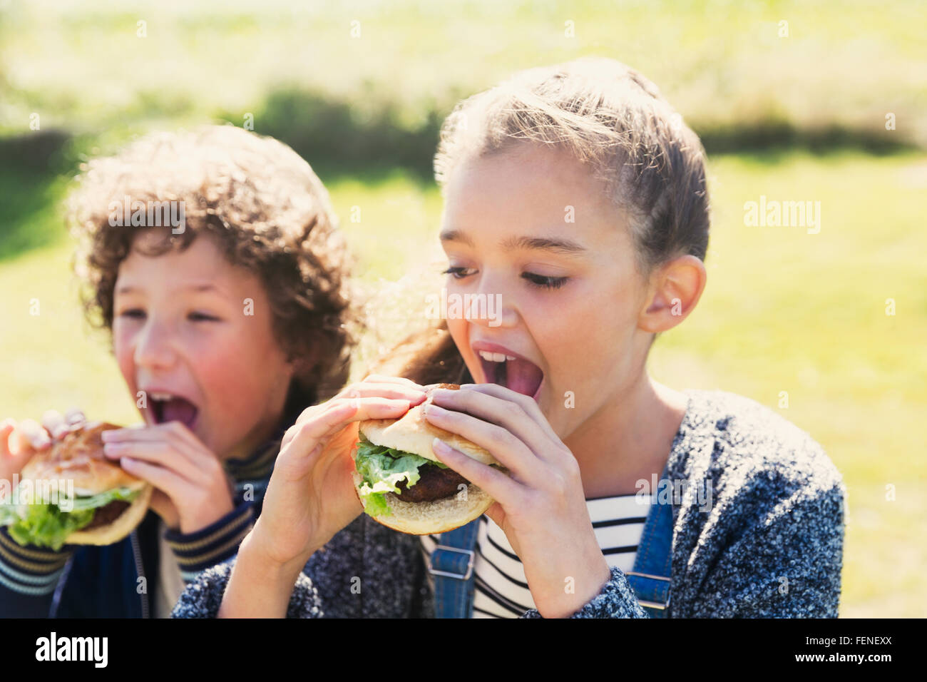 Brother and sister eating hamburgers outside Stock Photo