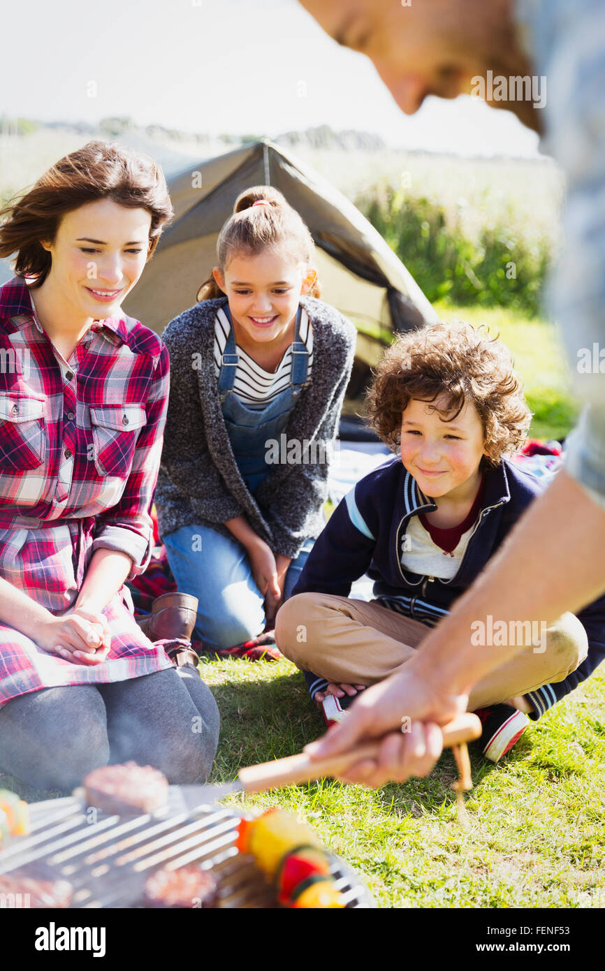 Family barbecuing at sunny campsite Stock Photo