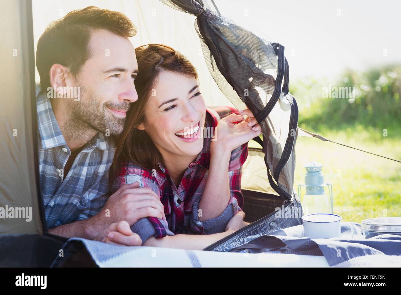 Smiling couple peering from inside tent Stock Photo
