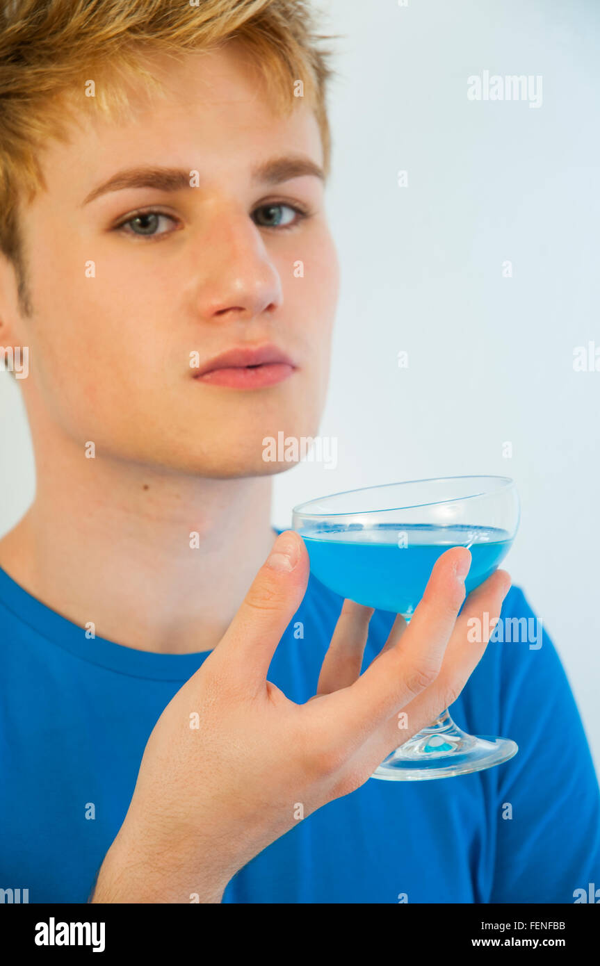 Young man drinking a blue isotonic drink, matching with his T-shirt. Close view. Stock Photo