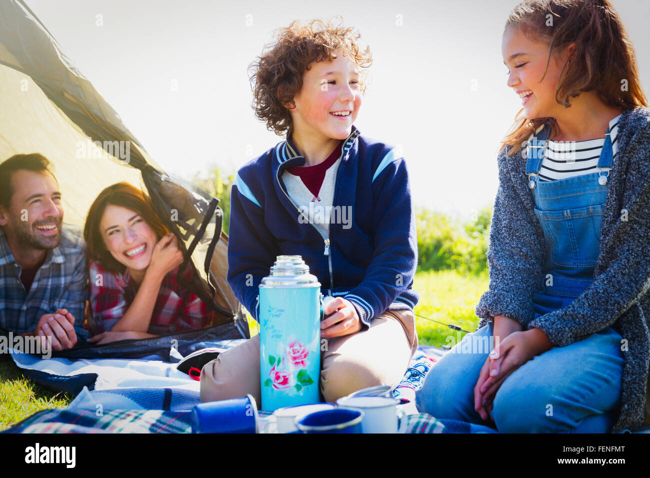 Smiling brother and sister with insulated drink container at campsite Stock Photo