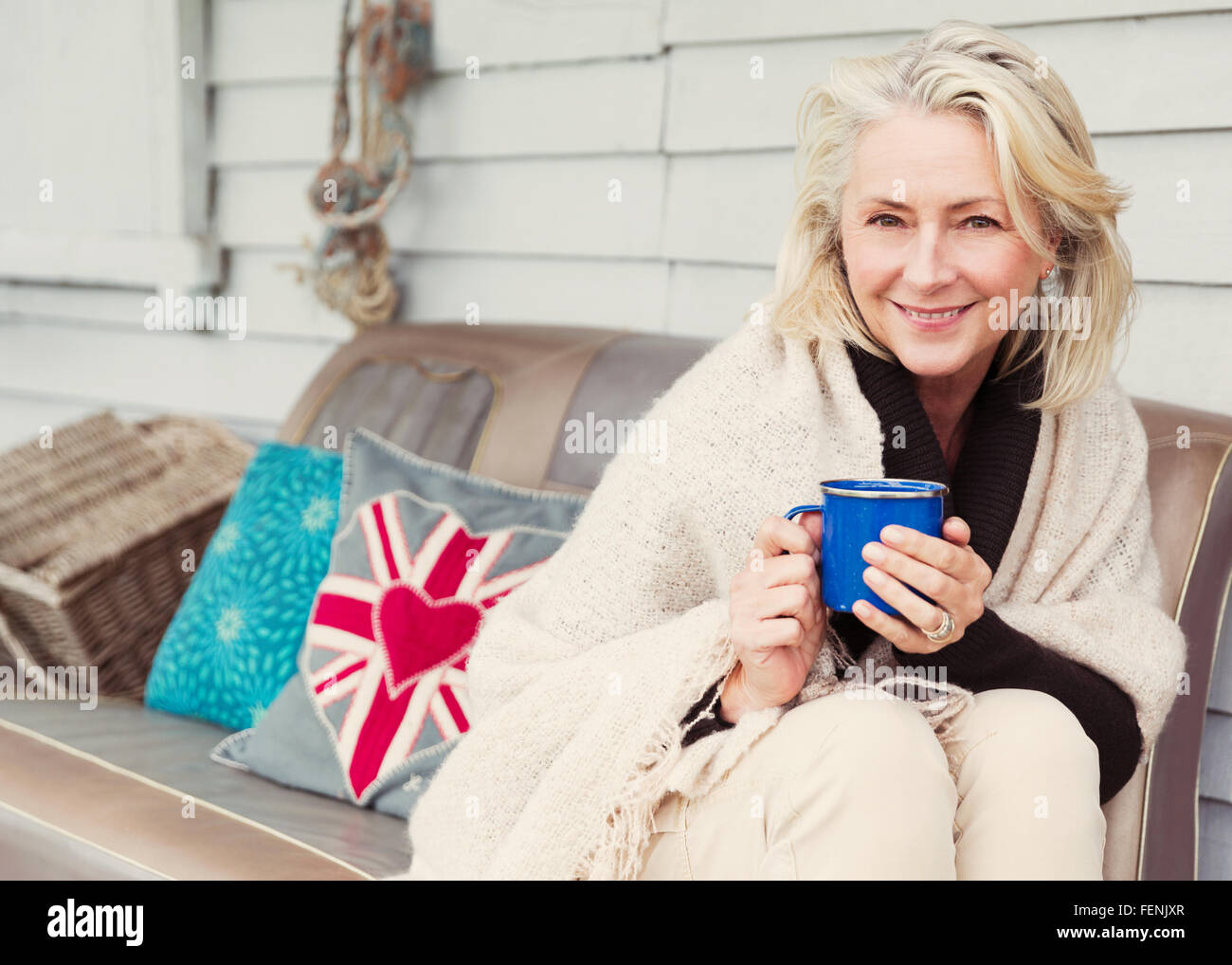 Portrait smiling senior woman drinking coffee on patio sofa Stock Photo ...