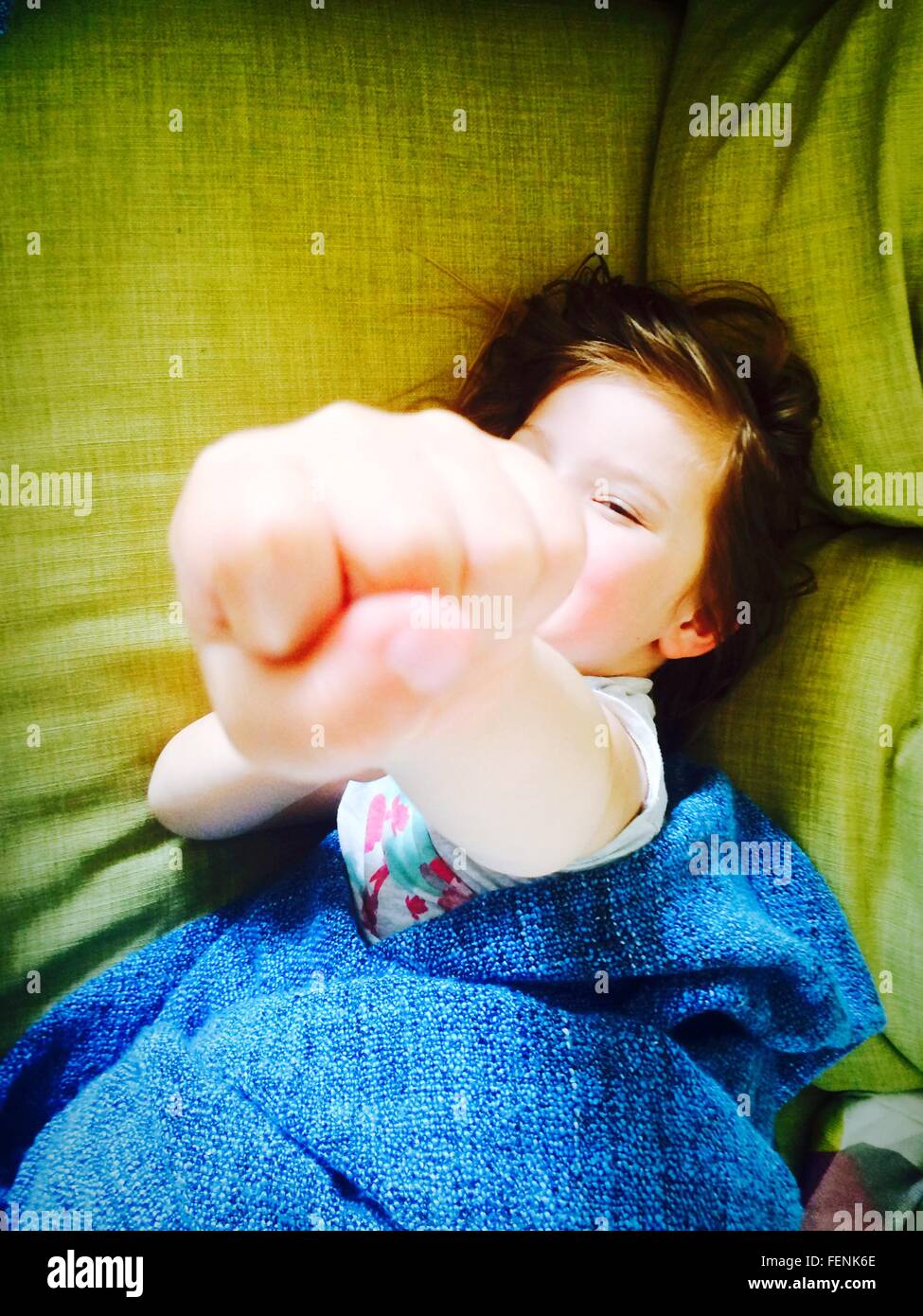 Portrait Of Girl Showing Fist While Relaxing On Bed Stock Photo