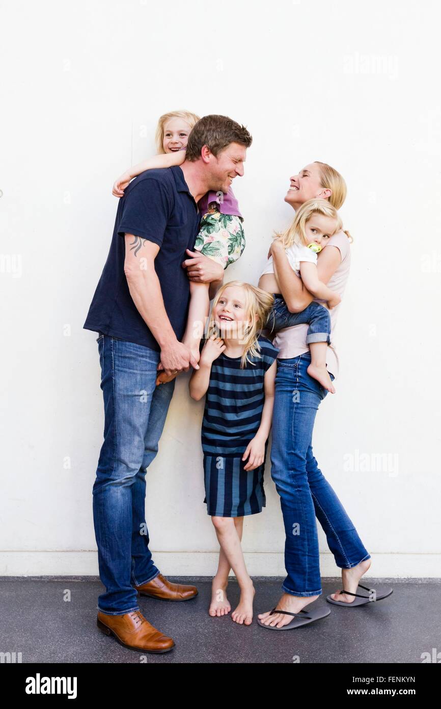 Portrait of parents and three young daughters in front of white wall Stock Photo