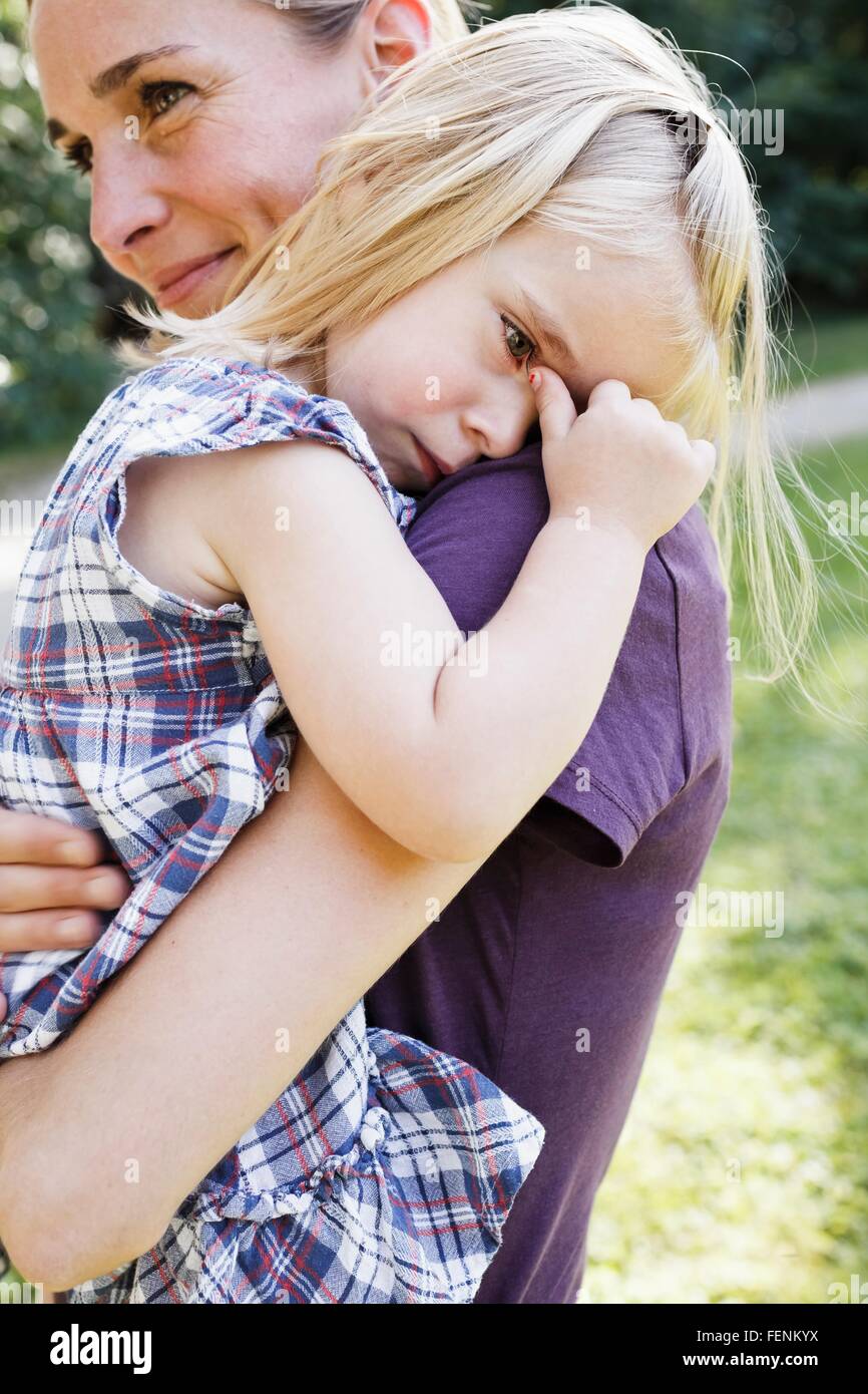 Mid adult woman carrying upset daughter in park Stock Photo