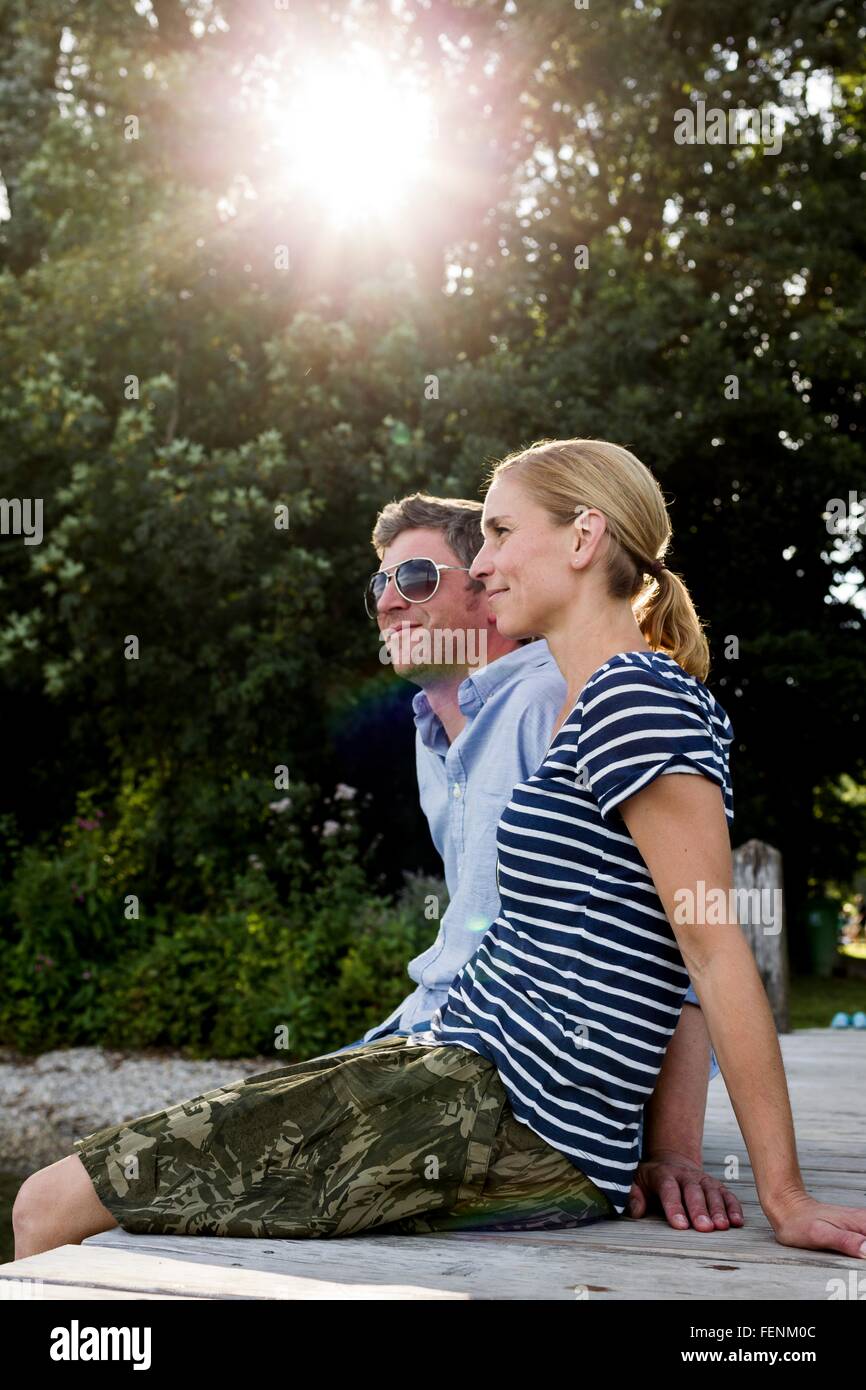 Couple sitting on wooden pier at lakeside Stock Photo