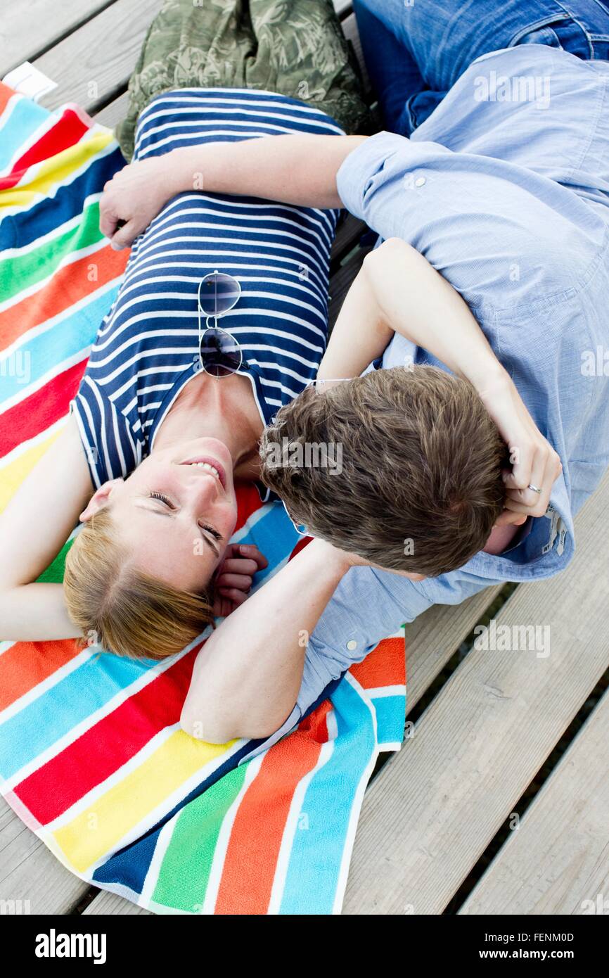 Overhead view of romantic couple sitting on wooden pier Stock Photo