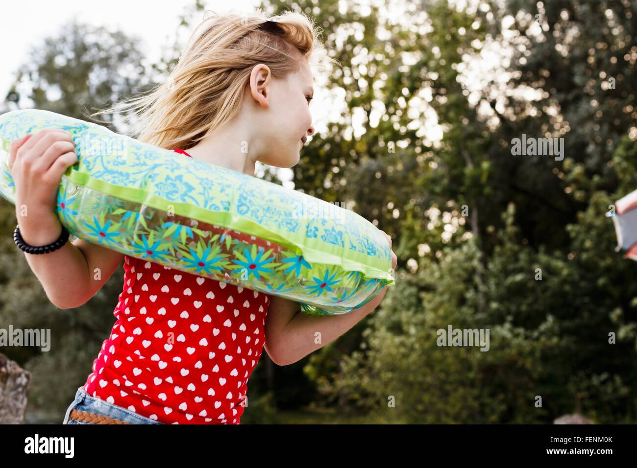 Girl playing with inflatable ring around her neck in park Stock Photo
