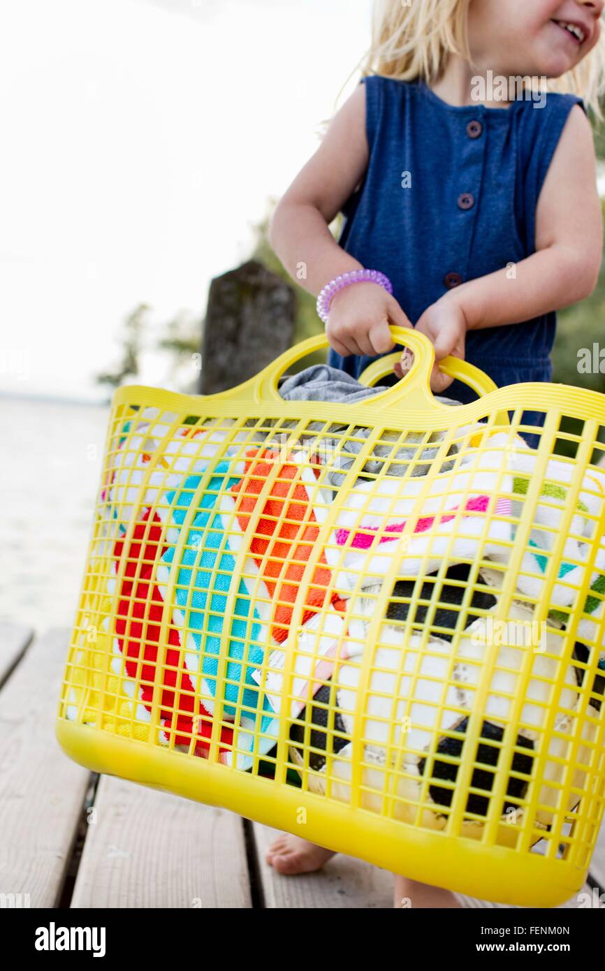 Cropped view of female toddler carrying yellow basket on wooden pier, Lake Starnberg, Bavaria, Germany Stock Photo