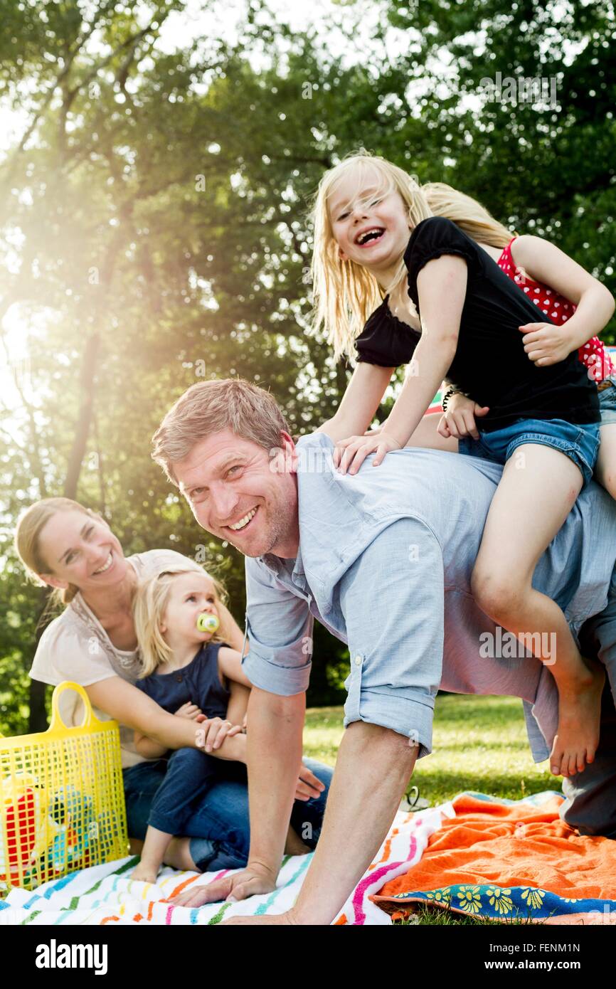 Father giving daughters piggyback at family picnic in park Stock Photo