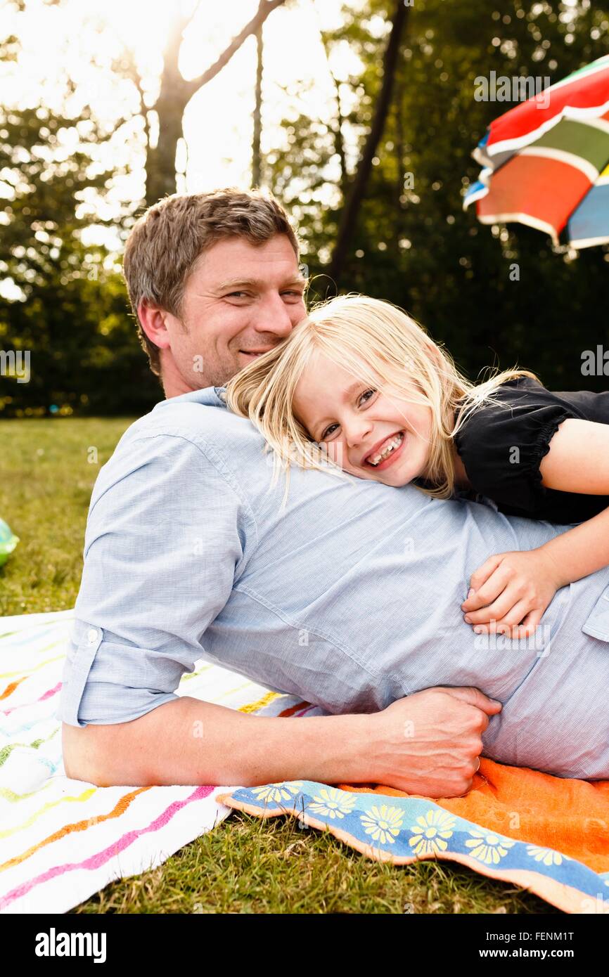 Portrait of mature man lying in park with daughter Stock Photo
