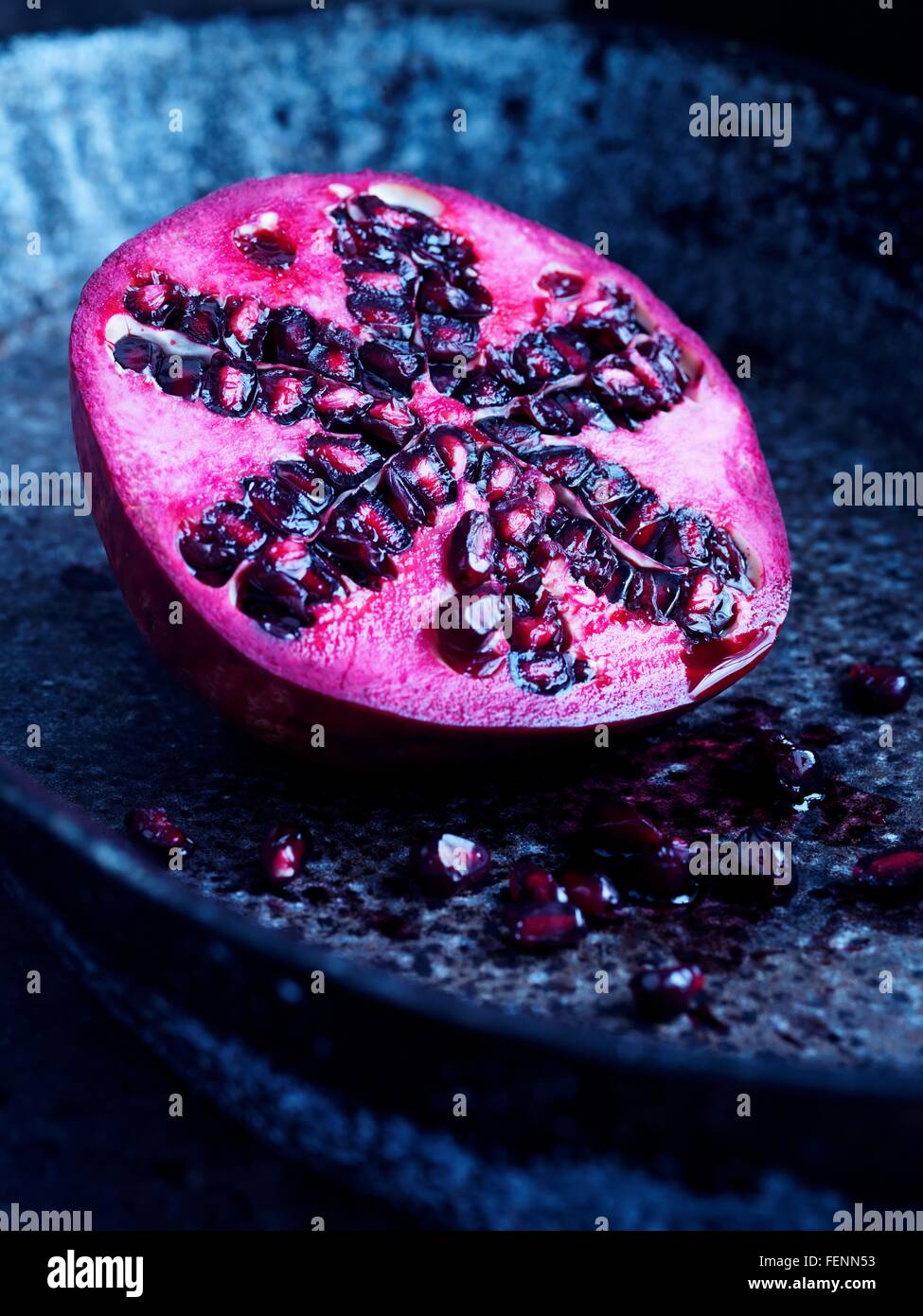 Half a pomegranate on blue plate Stock Photo