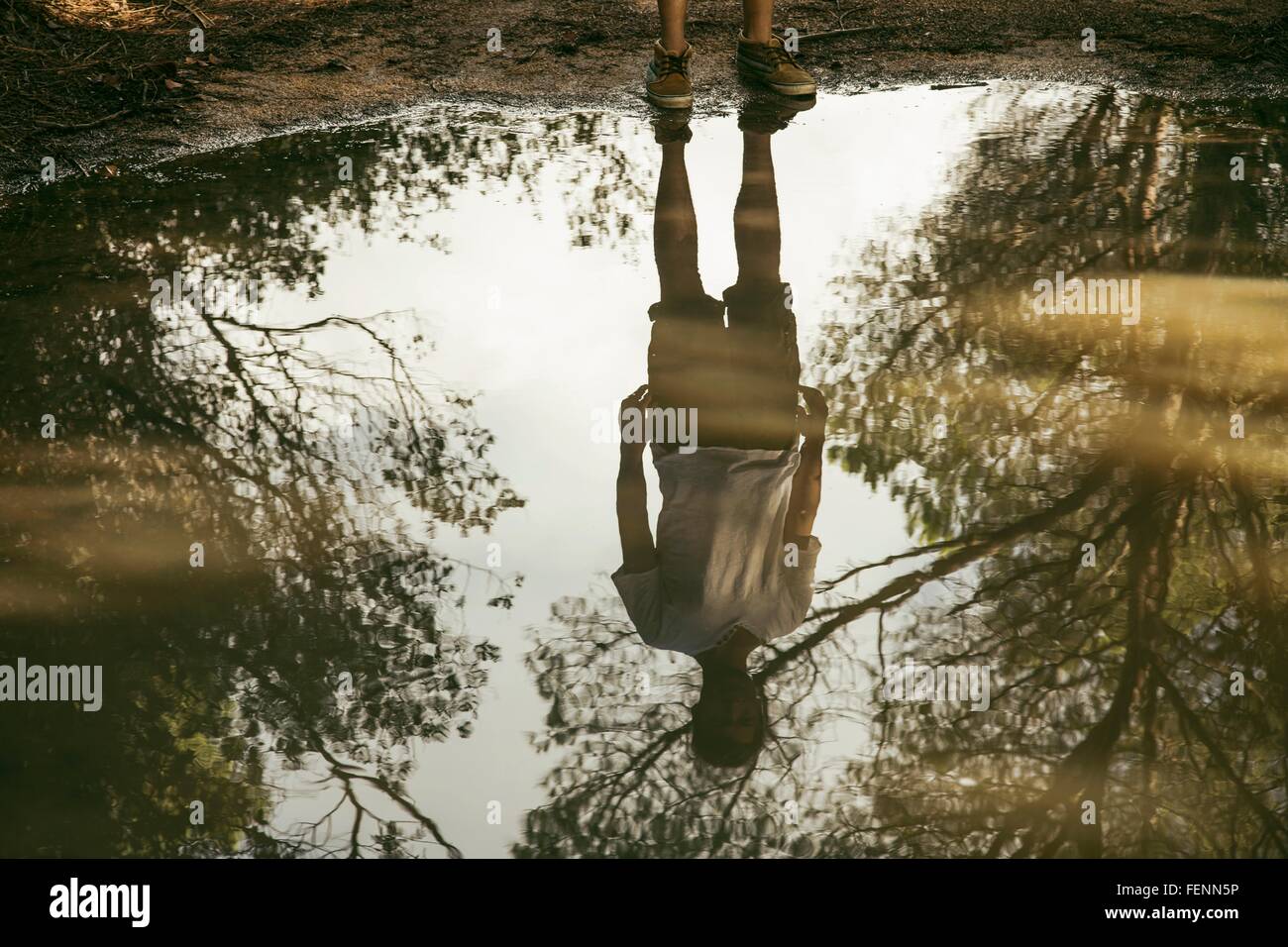 Full length reflection of young man in puddle, Costa Smeralda, Sardinia, Italy Stock Photo