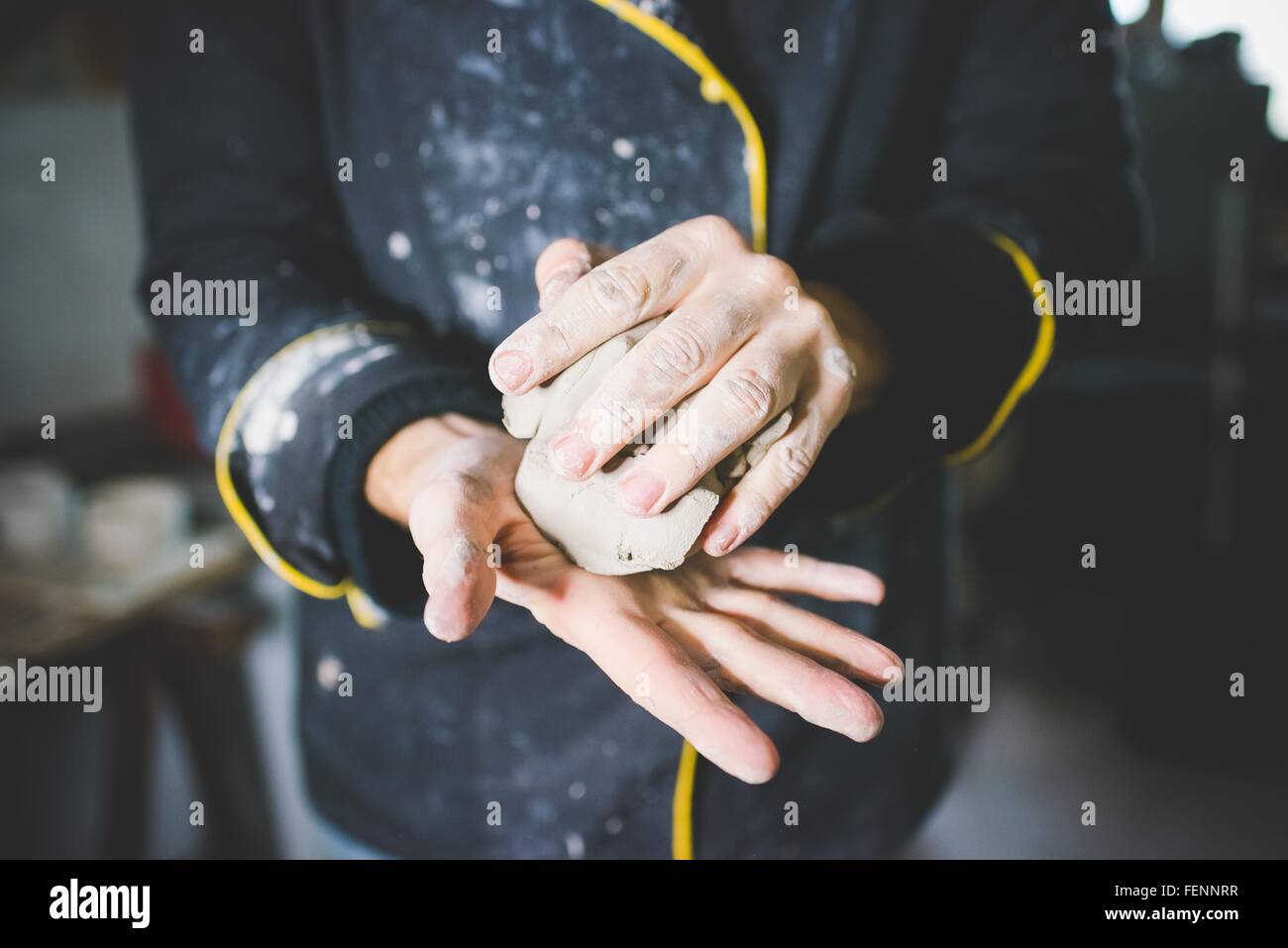 Cropped view of mid adult man squeezing clay in hands Stock Photo