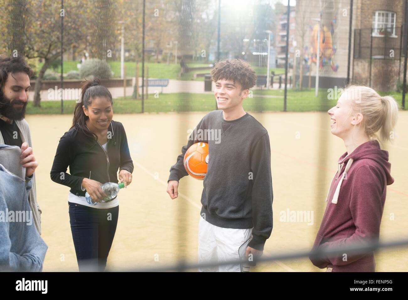 Group of adults standing on urban sports pitch, talking Stock Photo