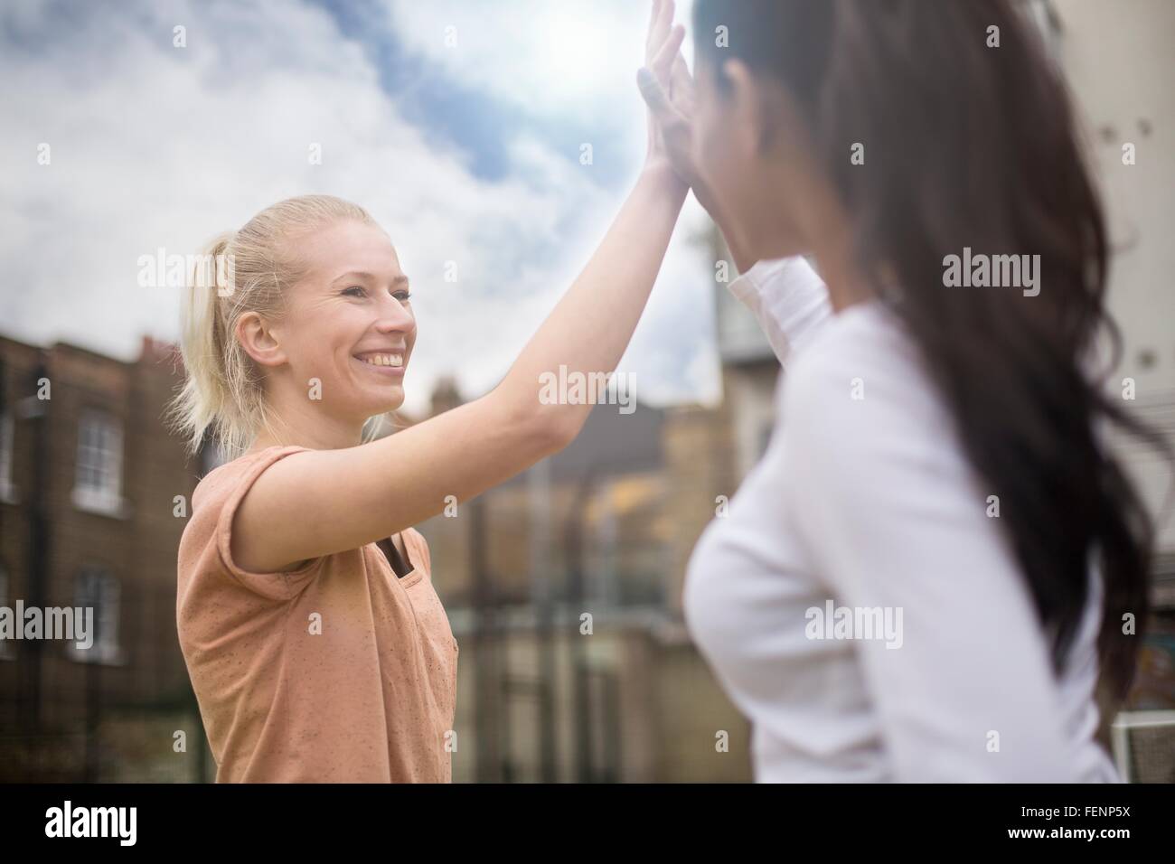 Two young women giving high five, outdoors Stock Photo Alamy