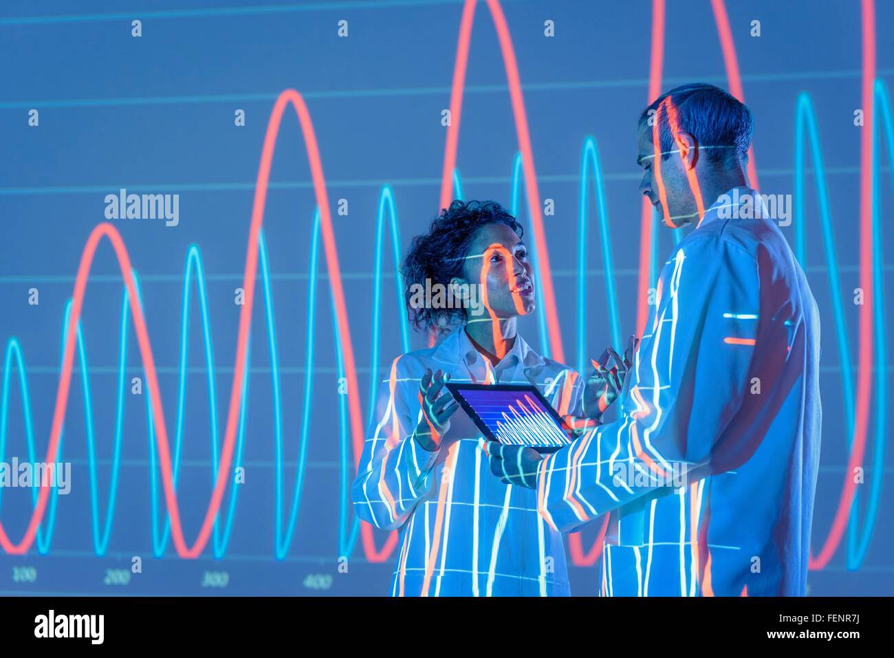 Scientists in discussion with graphical data projection Stock Photo