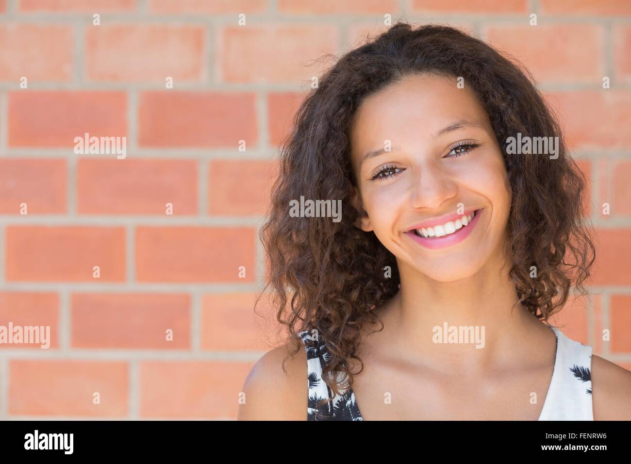 Portrait of happy girl in front of brick wall Stock Photo