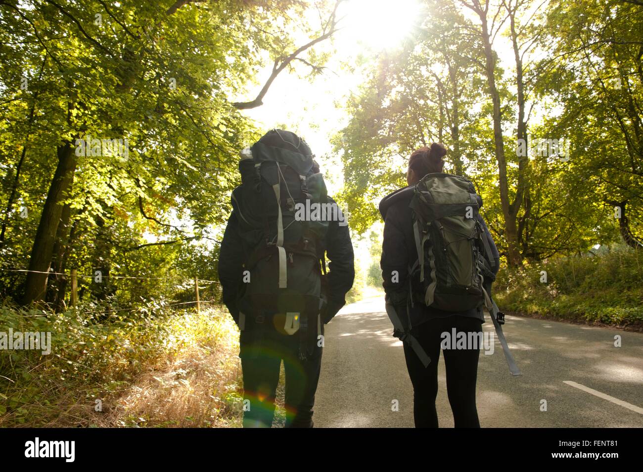 Rear view of young hiking couple on rural road Stock Photo - Alamy
